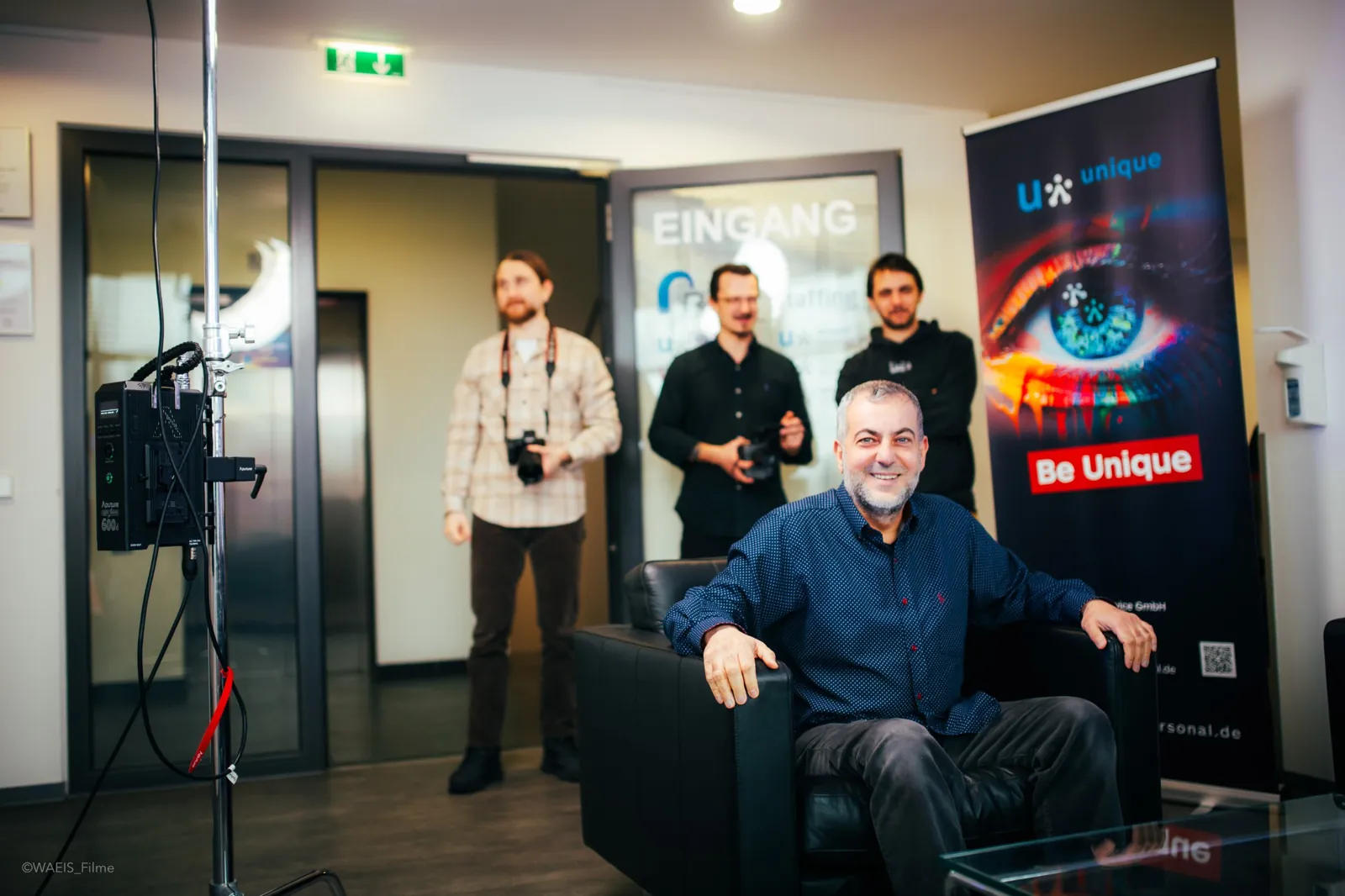 Das Team gemeinsam mit einem Interviewpartner vor dem unique-Banner
