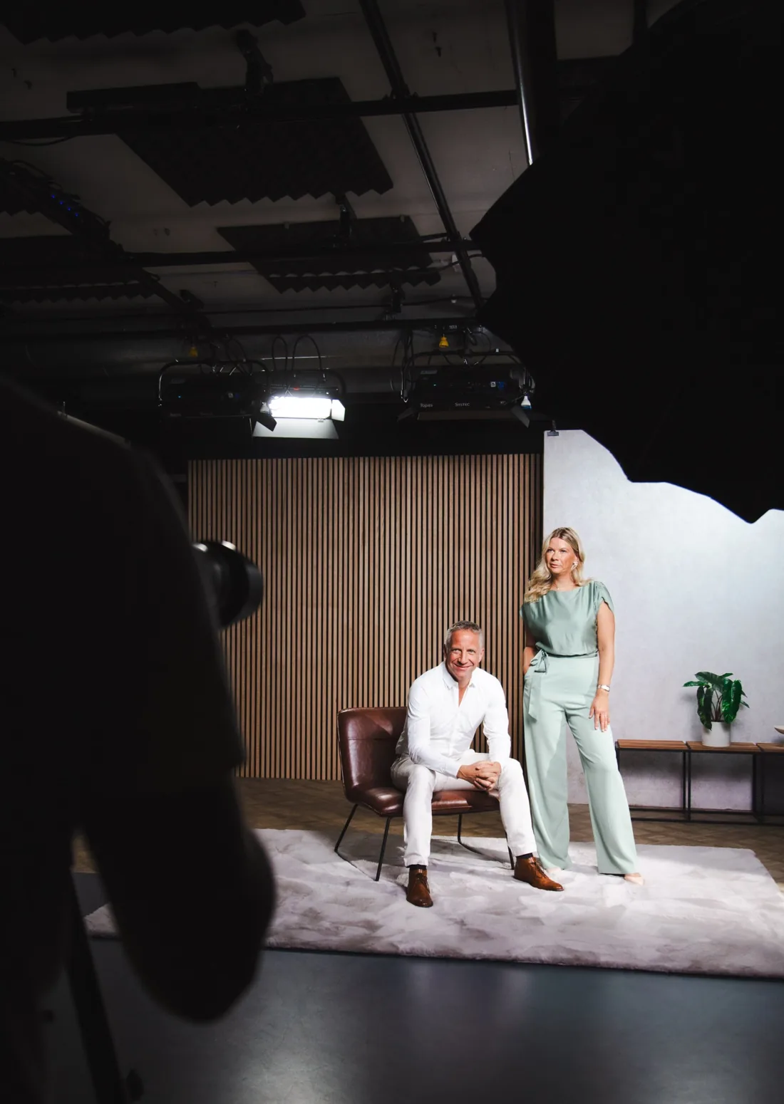 Ein Paar posiert auf dem Studio-Set, im Vordergrund die Silhouette von Kamera und Lichtwanne